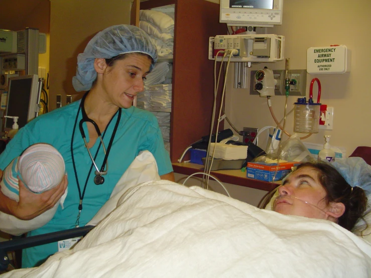 a woman laying in bed with a nurse nearby