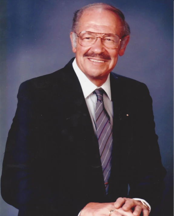 an older man in suit and tie with his hand on his hip