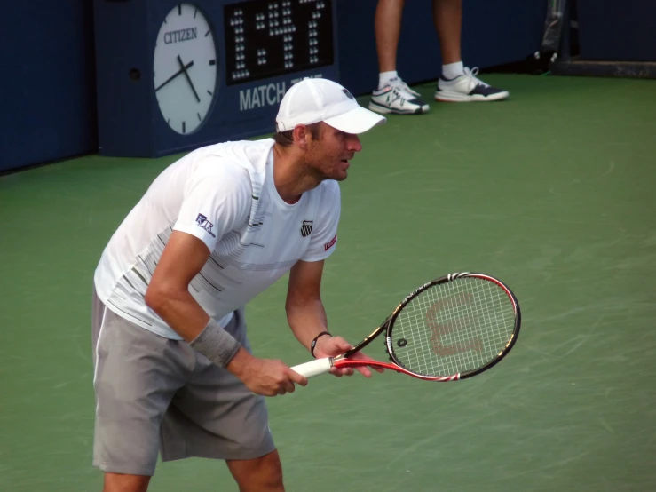 tennis player in white cap and gray shorts playing on tennis court