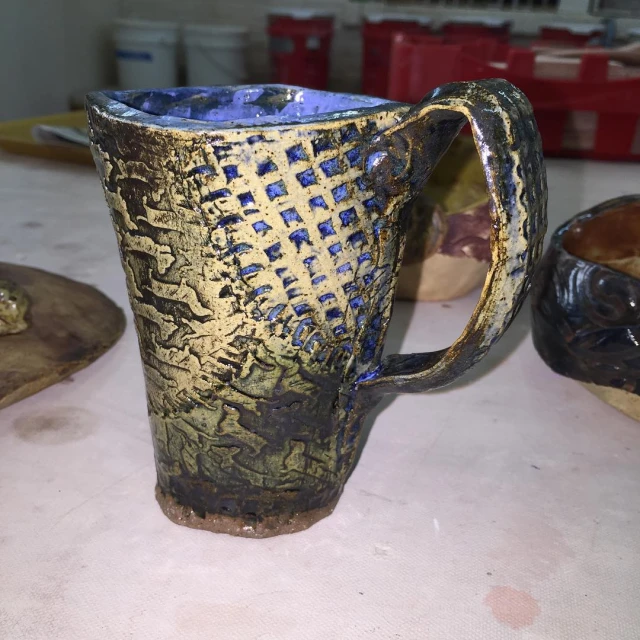 a blue and gold ceramic cup is sitting on a table