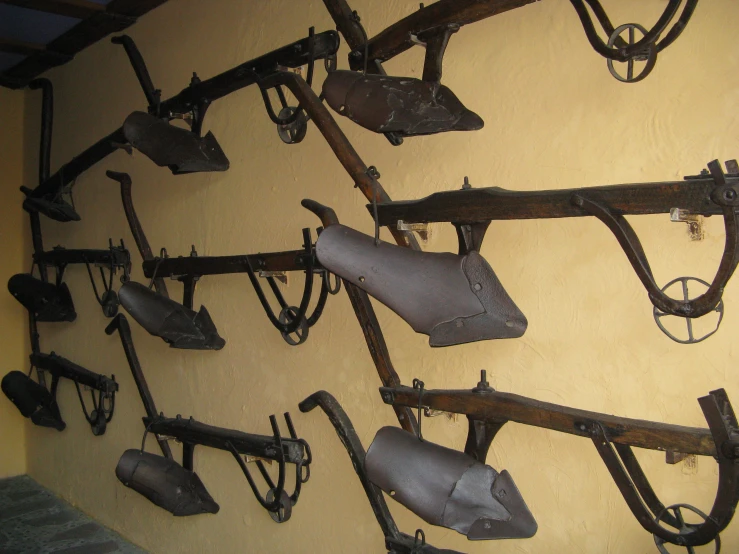 an assortment of guns hanging on a wall with hooks