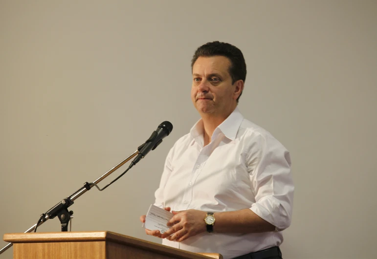 a man speaking from a podium with microphone behind him