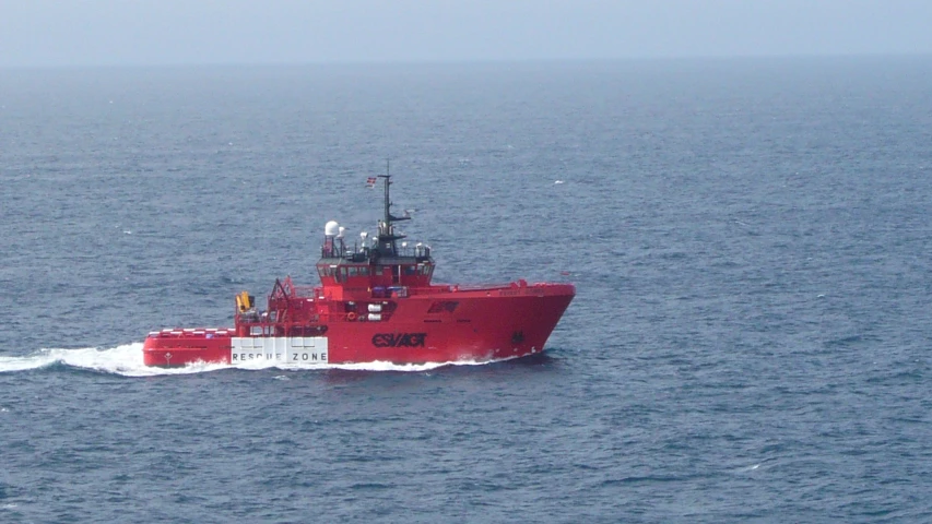 a red boat is in the water on a sunny day