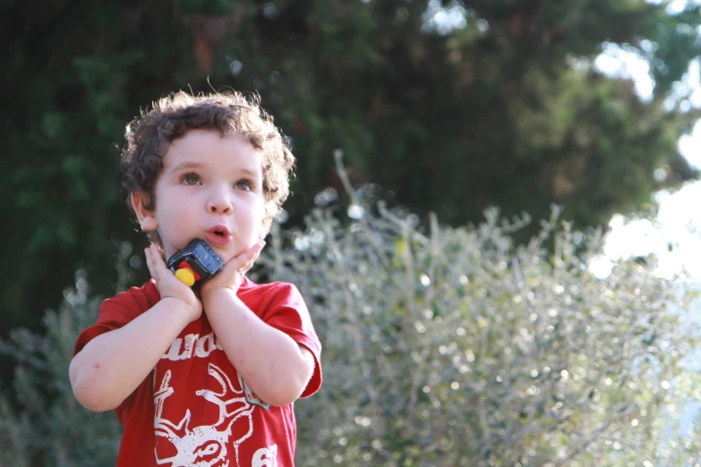 a little boy wearing a red shirt is eating soing