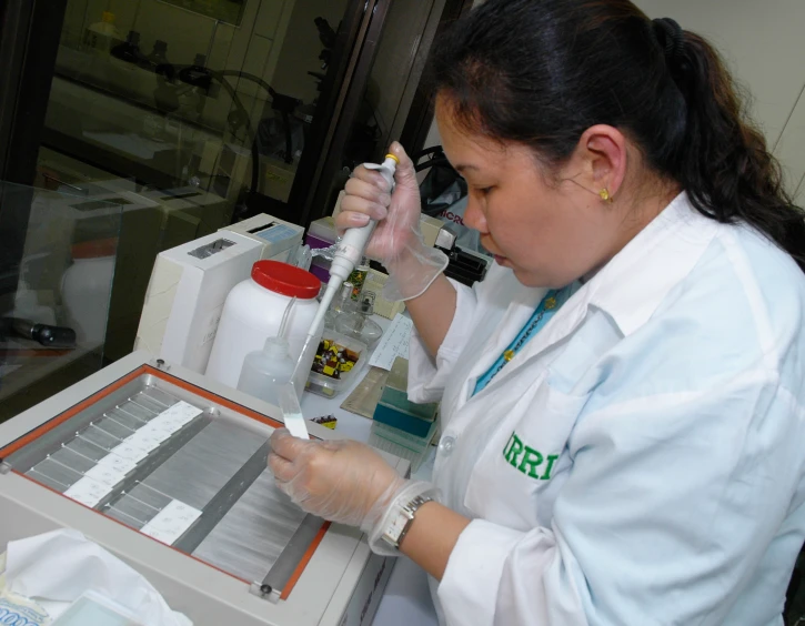 a female scientist working in a lab holding a syring up to two tubes of 