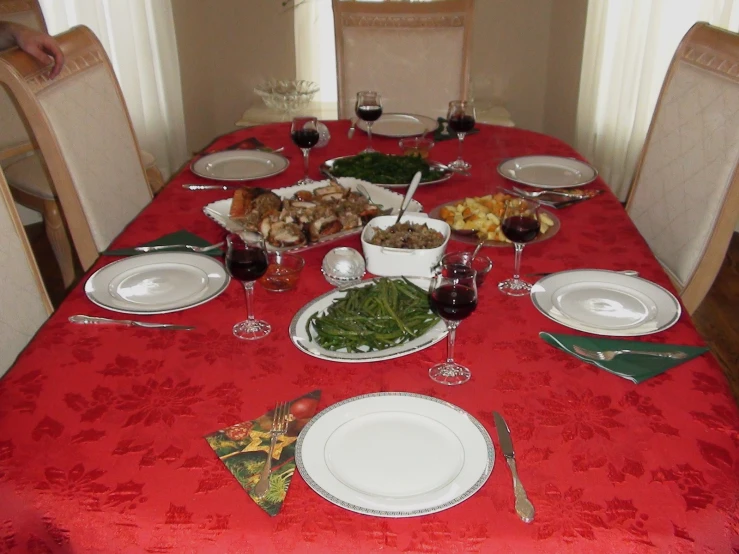 a red table set for six with glasses and plates of food