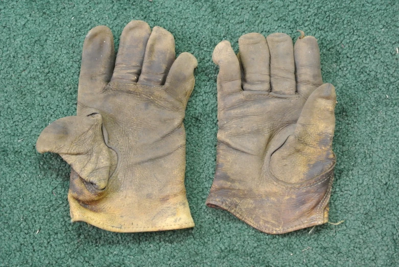 an old pair of dirty leather gloves laying on the floor