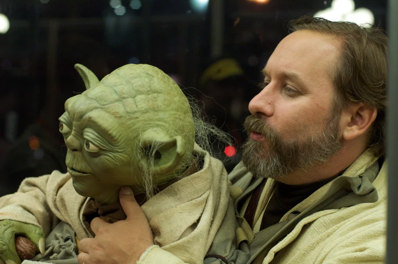 a man is holding a yoda mask at the convention