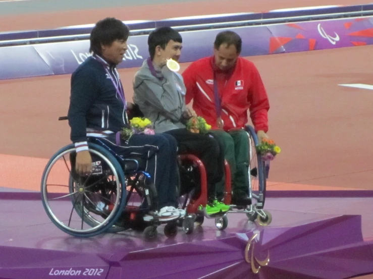 two men are shaking hands with one man in a wheelchair