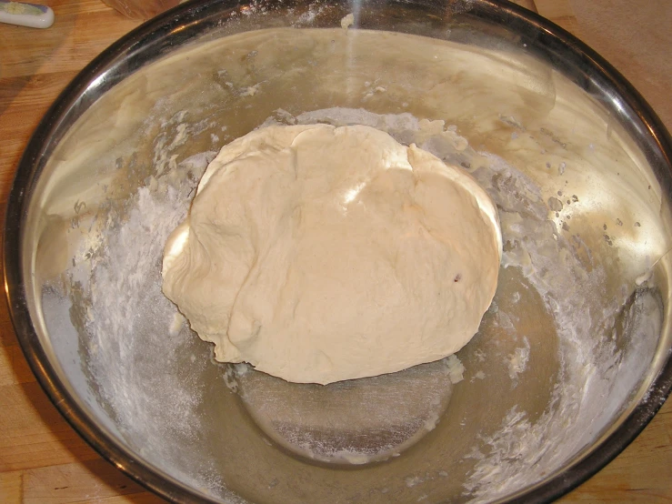 dough being mixed in a silver bowl on a wooden surface
