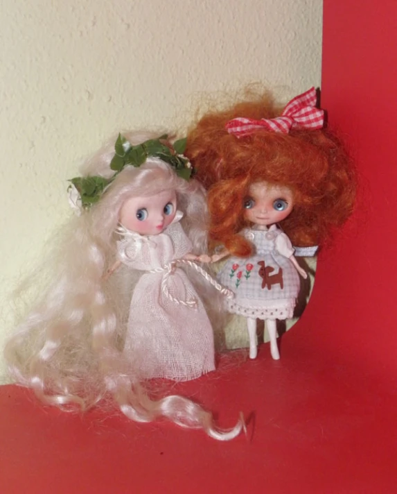 there are two dolls sitting on a red surface