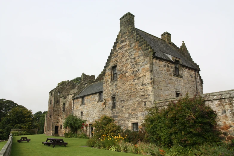 a large stone building with several windows and grass and bushes in front