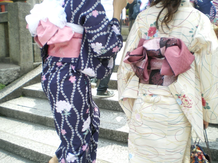 two people dressed in kimonos and holding onto the back of a purse