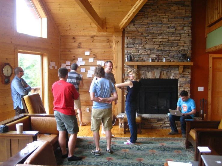 several people are standing in a living room with a fire place