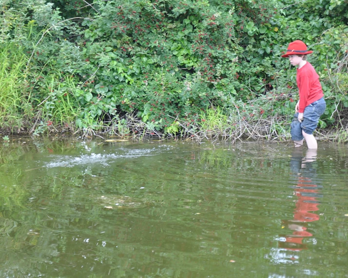 a man is wading through the water with a fish in his hand