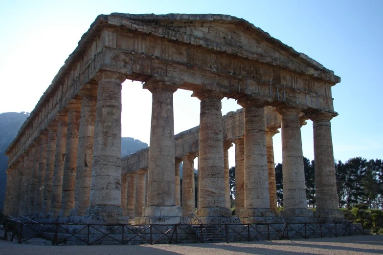 an old structure with two pillars sitting in front of a mountain