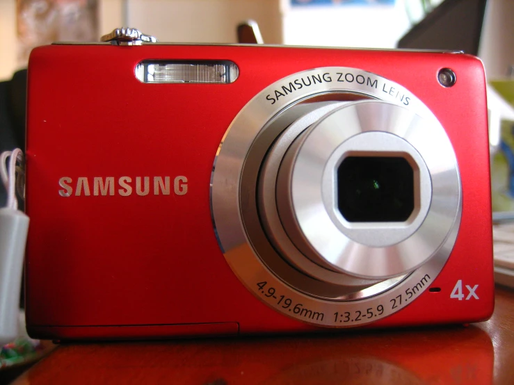 a red samsung digital camera sitting on top of a table