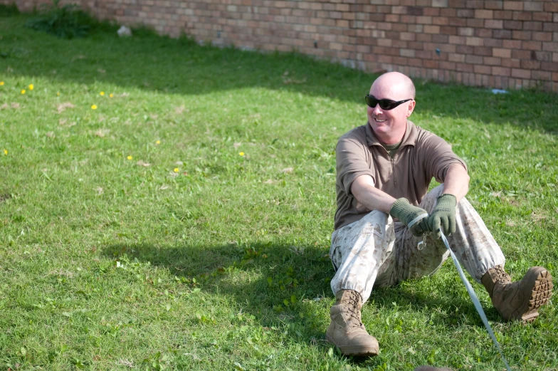 a man sits in the grass with a sheep