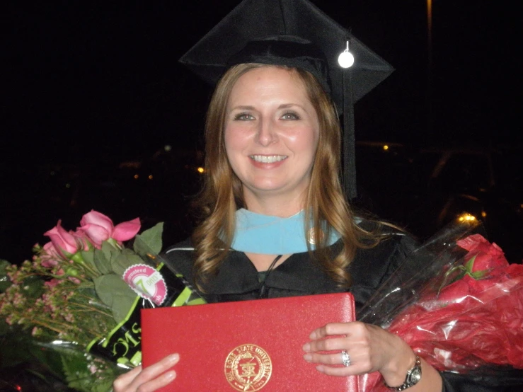 a woman with a diploma holding flowers and books