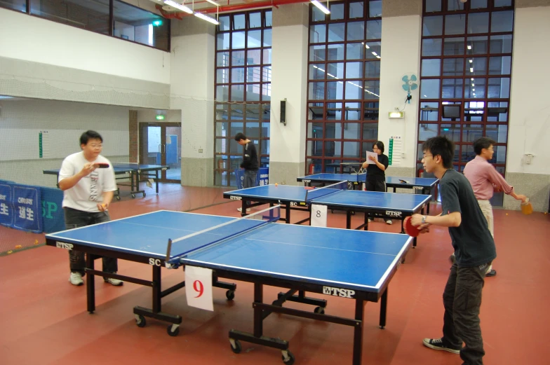 a group of people play ping pong in the gym