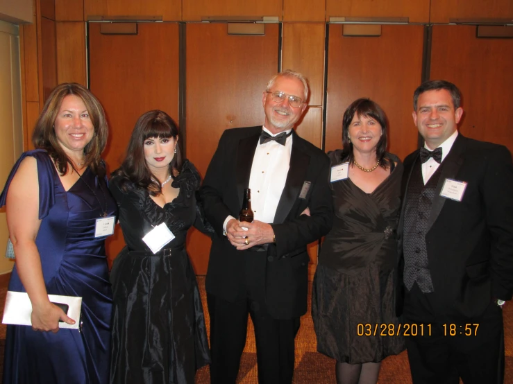 a group of people standing in a room wearing tuxedos