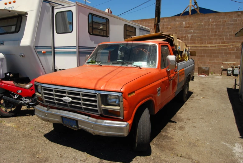 an old ford pick up with a trailer in the background