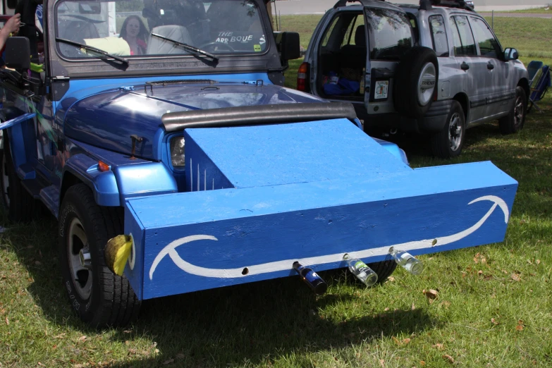 a blue truck with an upside down bed parked next to other cars