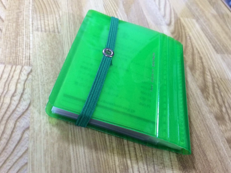 a green binder is laying on a wood table