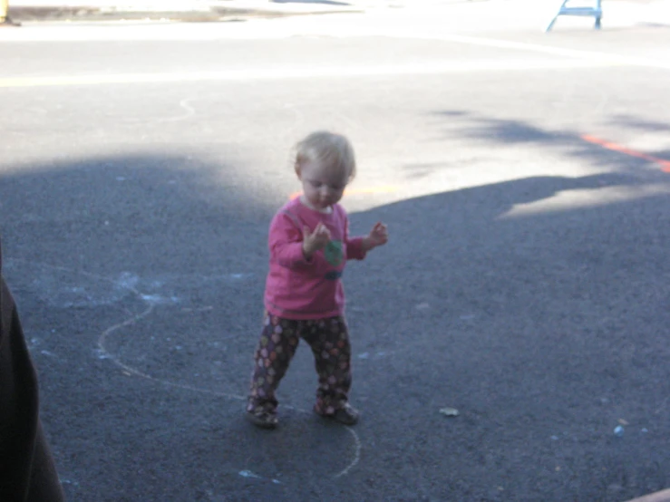 little child standing on asphalt next to road