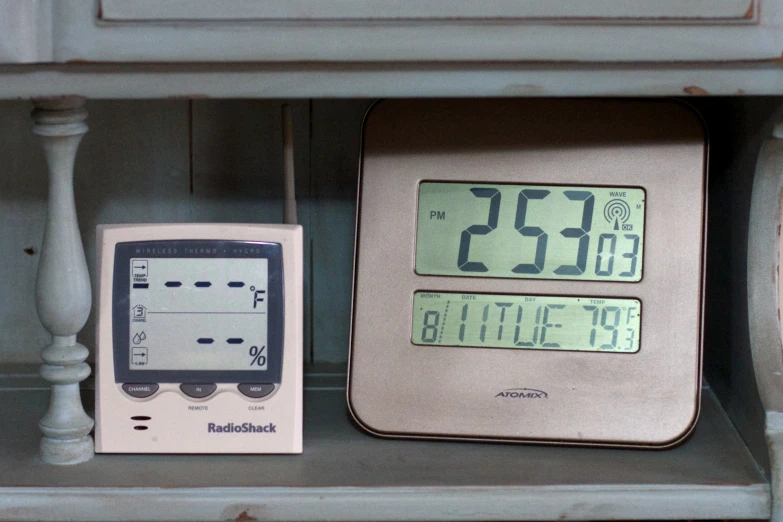 clock sitting next to thermometer in a cupboard