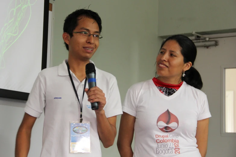 an asian man holding a microphone and standing next to an oriental woman