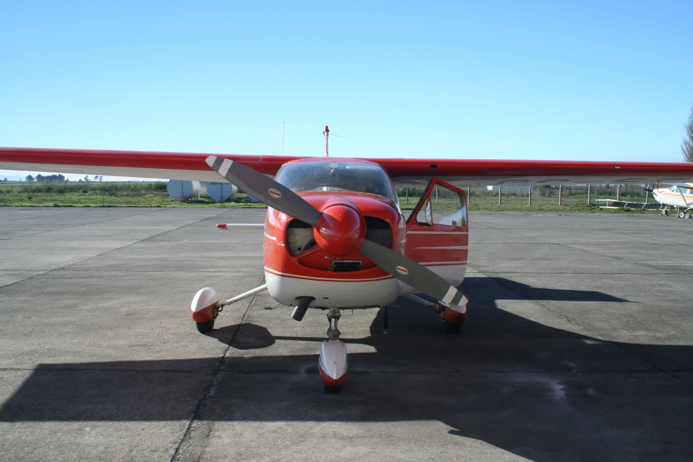 red and white plane with black wings sitting on an asphalt runway