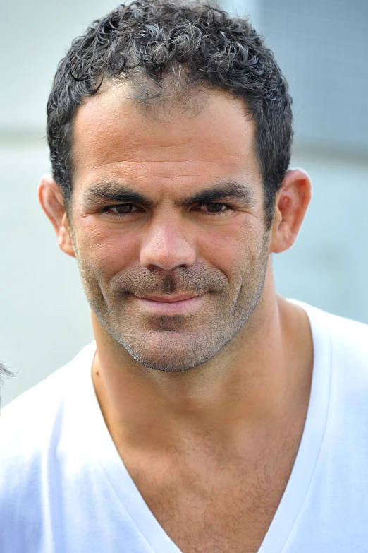 a man with gray hair and white tee shirt looking at camera