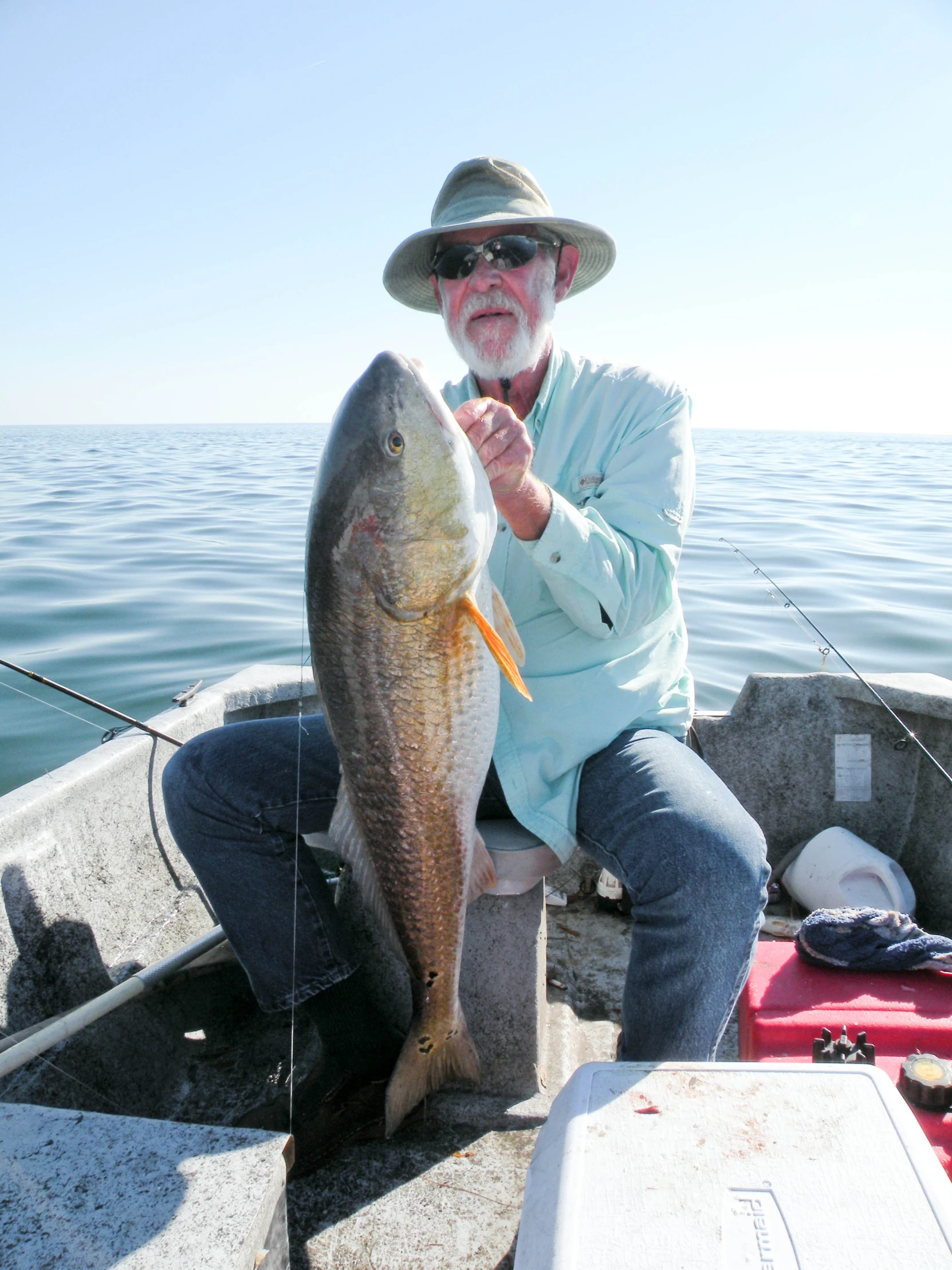 an old man holding a large fish in a boat