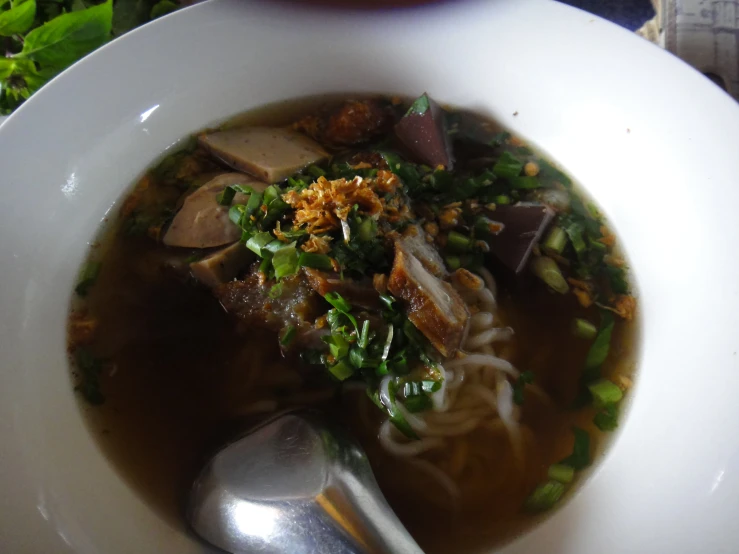 a white bowl filled with noodle soup on top of a wooden table