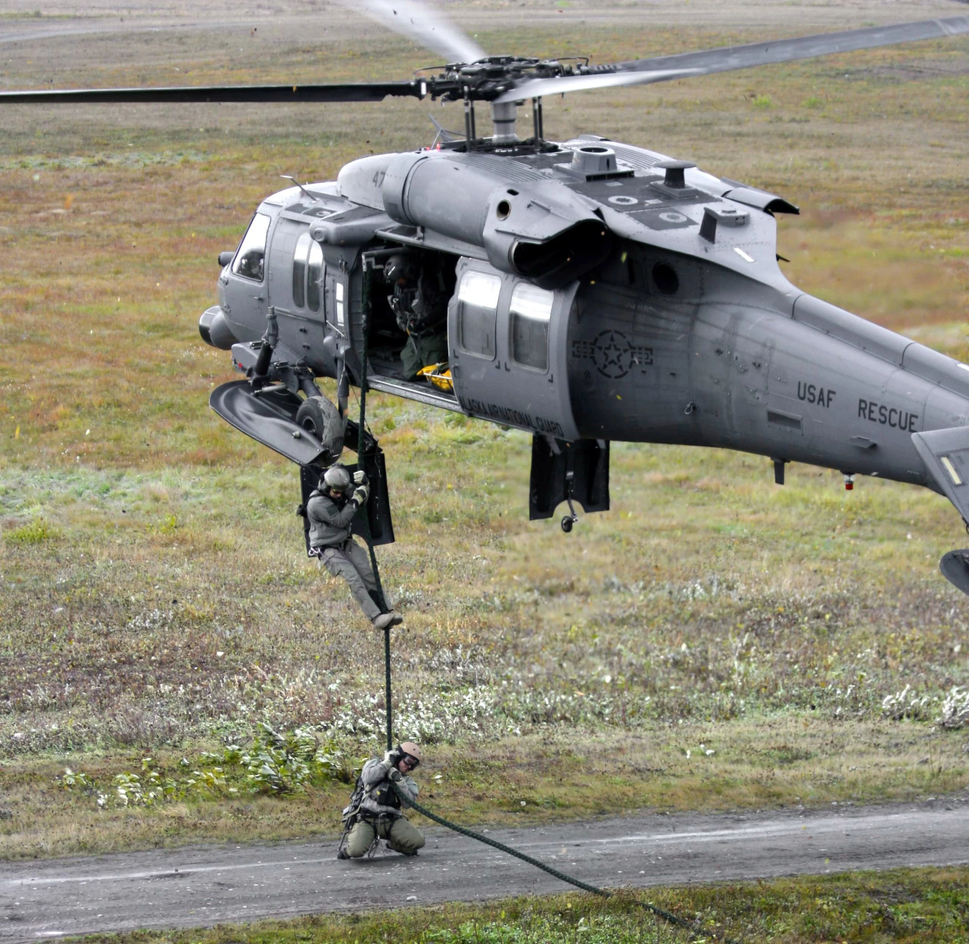 an helicopter with its pilot at the ready while another man is near by