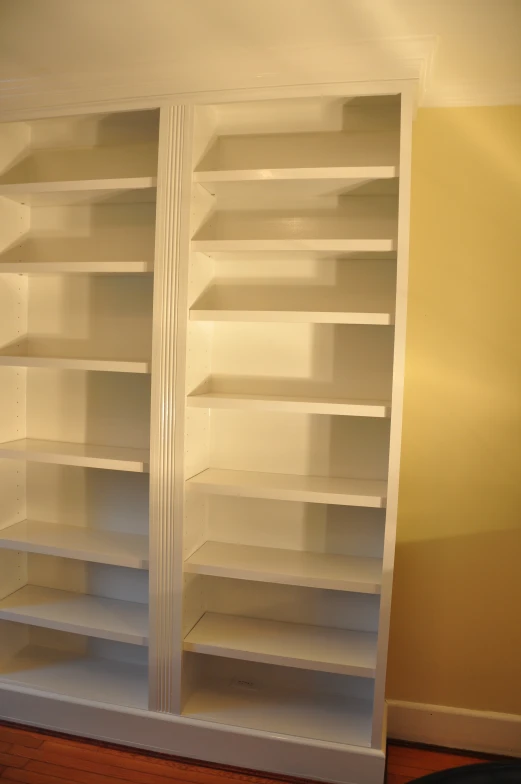 two shelves of white empty shelving in the corner of a room