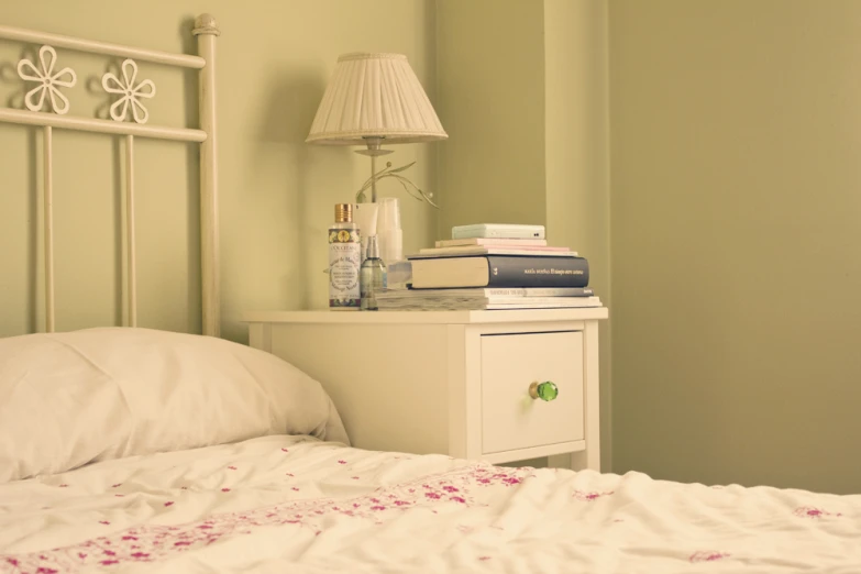 there is a nightstand with a lamp next to a bed