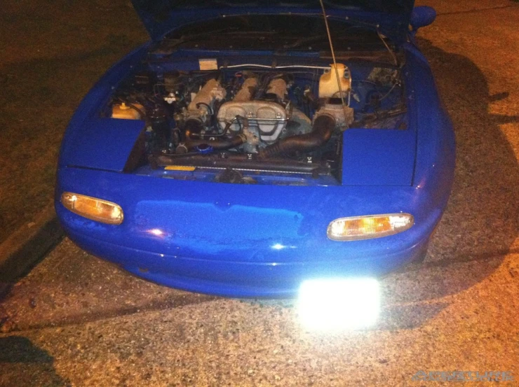 the front end of a blue car with its hood open