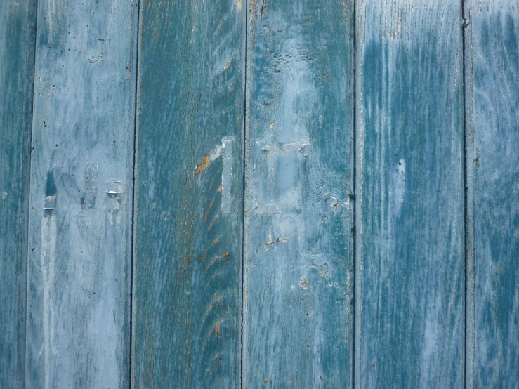 the light blue wood is peeling paint from a barn