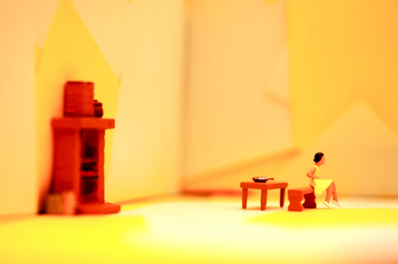 a model of a chair, table, and two stools in front of yellow walls