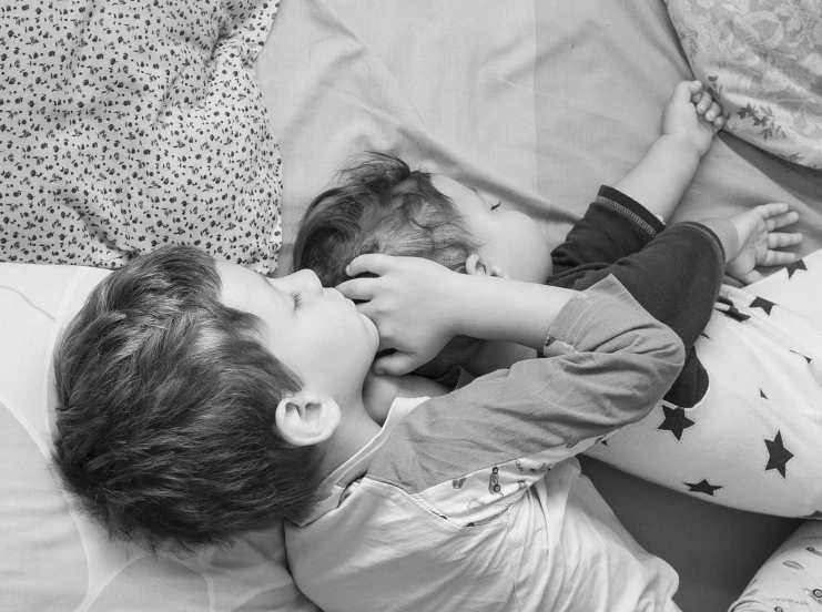 a child kissing another child on the bed