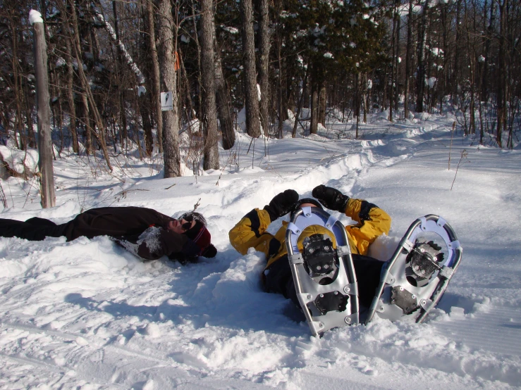 two snow boarders sitting on the ground in the woods