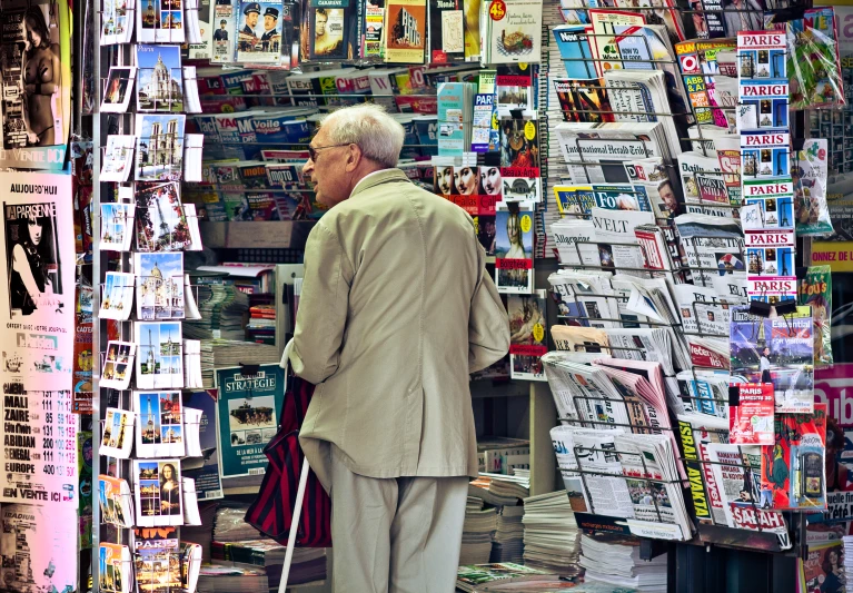 an older man standing in front of a newspaper stand