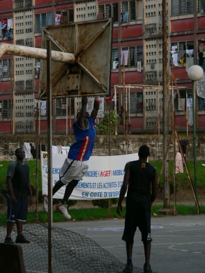 young men playing basketball outside in a city