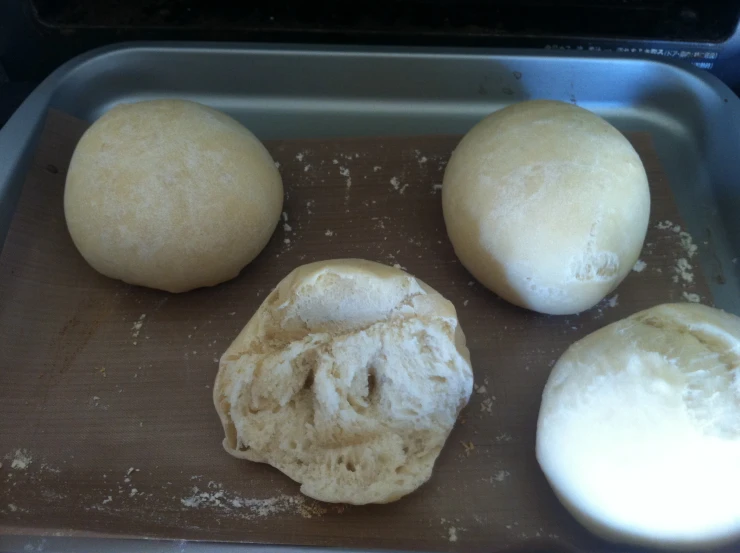 three large and two small bread rolls on a baking sheet