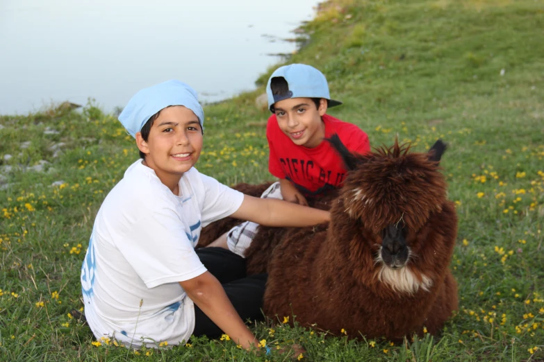 the boys are sitting on the grass with an animal