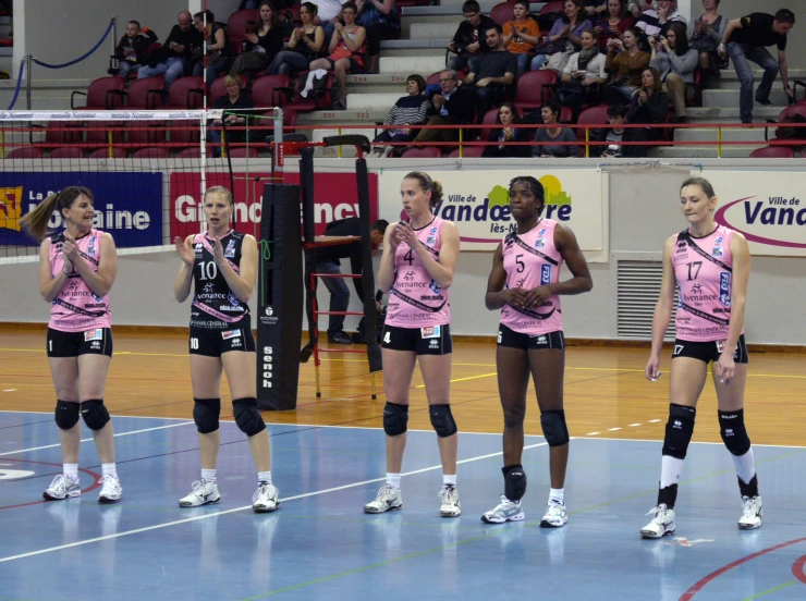 there are six female volleyball players standing next to each other