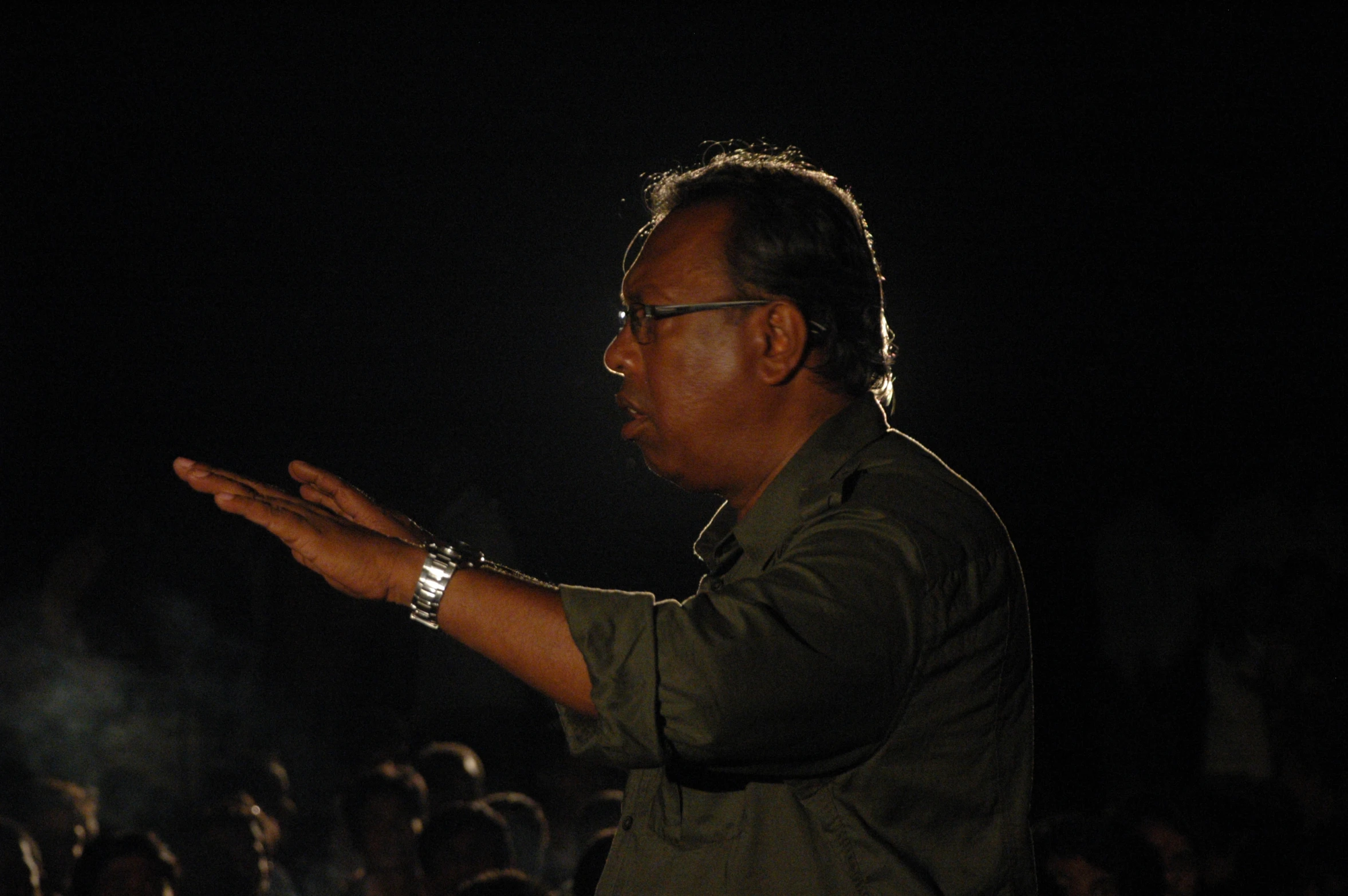 a man standing in front of an audience holding his hands out