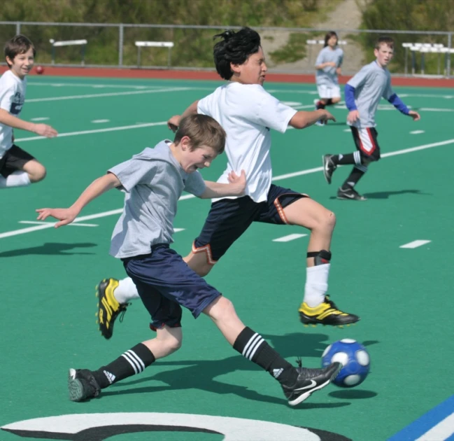 two boys fighting for the ball at a soccer game